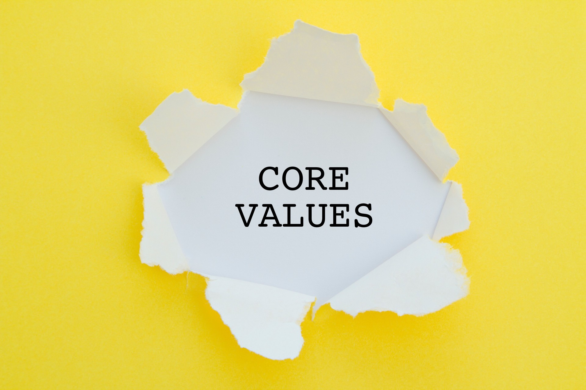 Core values word written under torn paper.
